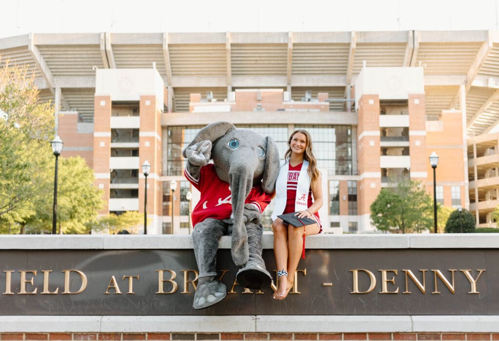 University of Alabama graduate posing with Big Al mascot in front of Bryant-Denny Stadium in Tuscaloosa Alabama